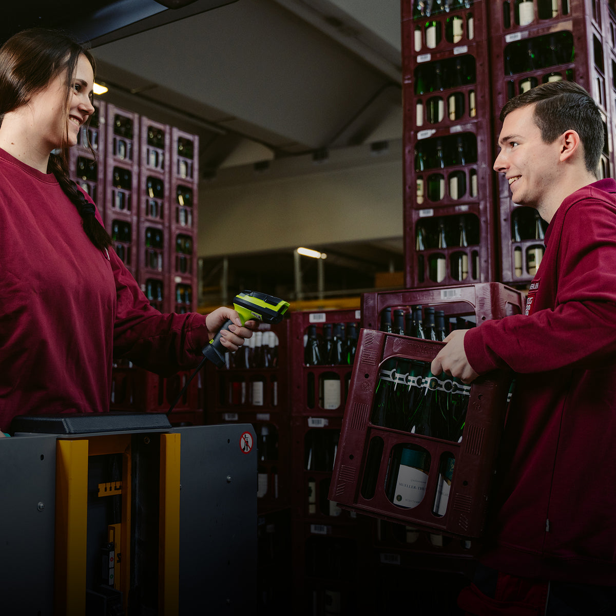 Zwei WZG Mitarbeitende scannen und transportieren Weinkisten im Lager