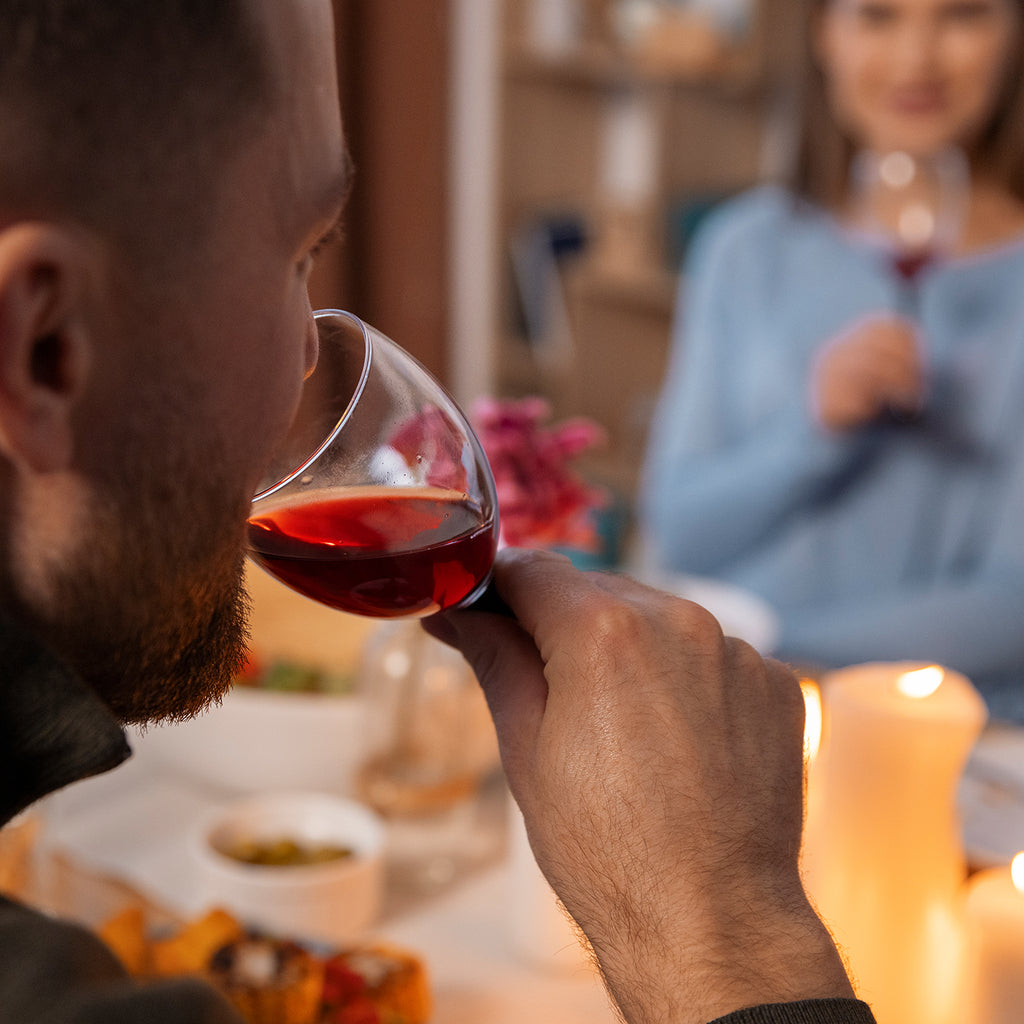 Mann verkostet ein Glas Rotwein aus dem Sortiment der WZG bei einem gemeinsamen Essen.