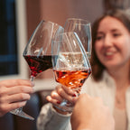 Frau die mit Freunden anstößt. In den Weingläsern sind unterschiedliche Weinsorten gefüllt. 