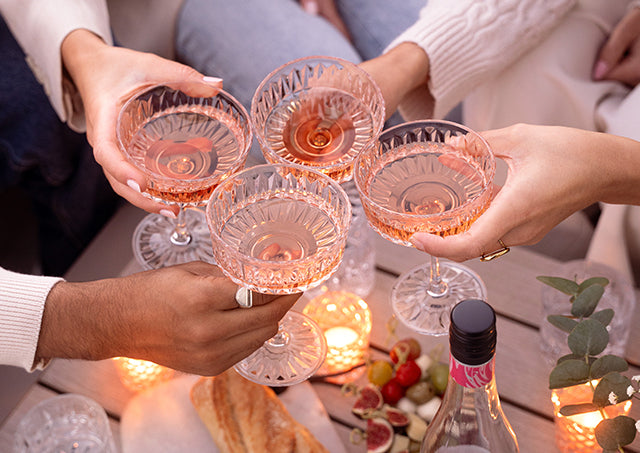 Mehrere Personen stoßen mit Roséwein von WZG in Weingläsern an.