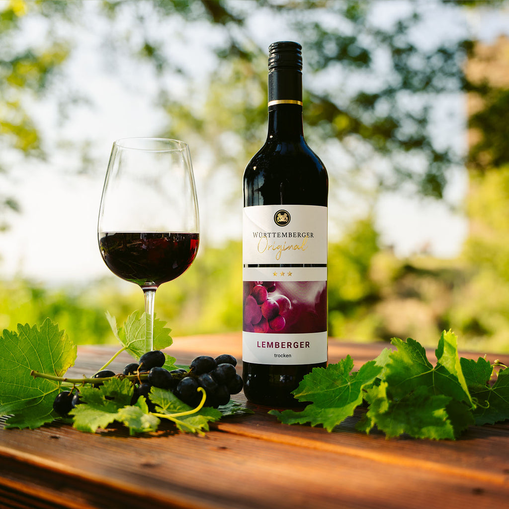 Württemberger Original Rotwein der WZG mit Weinglas als Begleitung zu einem gedeckten Tisch mit Weinblättern