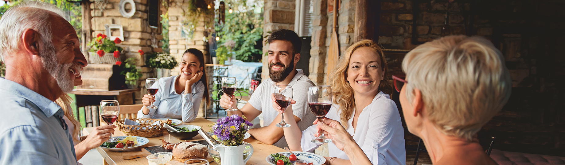 Gruppe von Erwachsenen am Tisch stoßen mit Rotwein an WZG Weinserie Württemberger Original